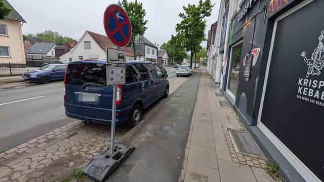 In einer Parkbucht an einer Straße steht ein Transporter. Vor der Parkbucht steht auf dem dortigen benutzungspflichtigen Radweg ein Halten-Verboten-Schild quer zur Fahrtrichtung. Unter dem Schild ein Hinweis, dass es am 13.04. gültig ist. Das Foto wurde am 06.05. aufgenommen.