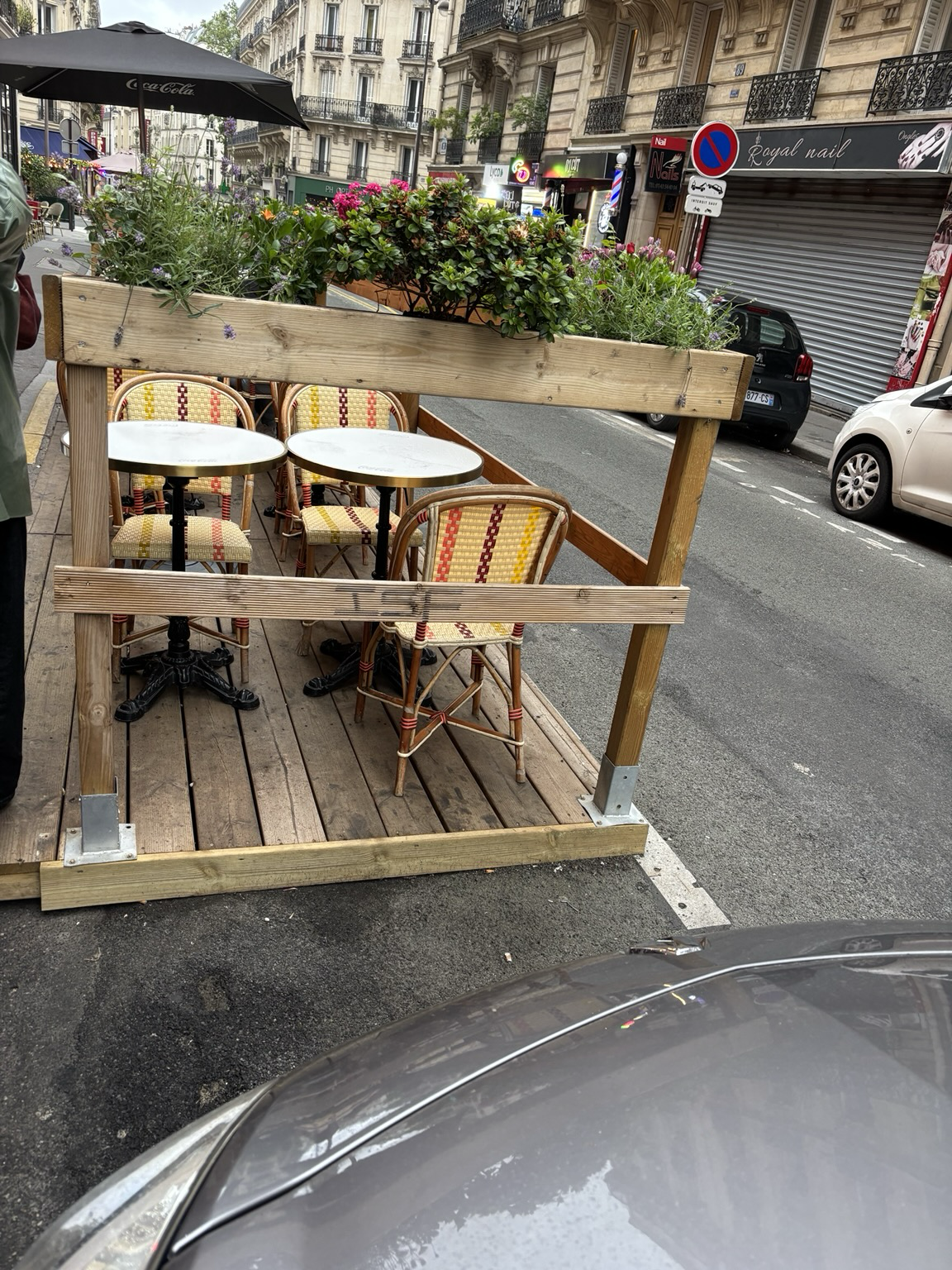 Improvisierte Holzveranda mit Stühlen und Tischen auf einem Parkstreifen