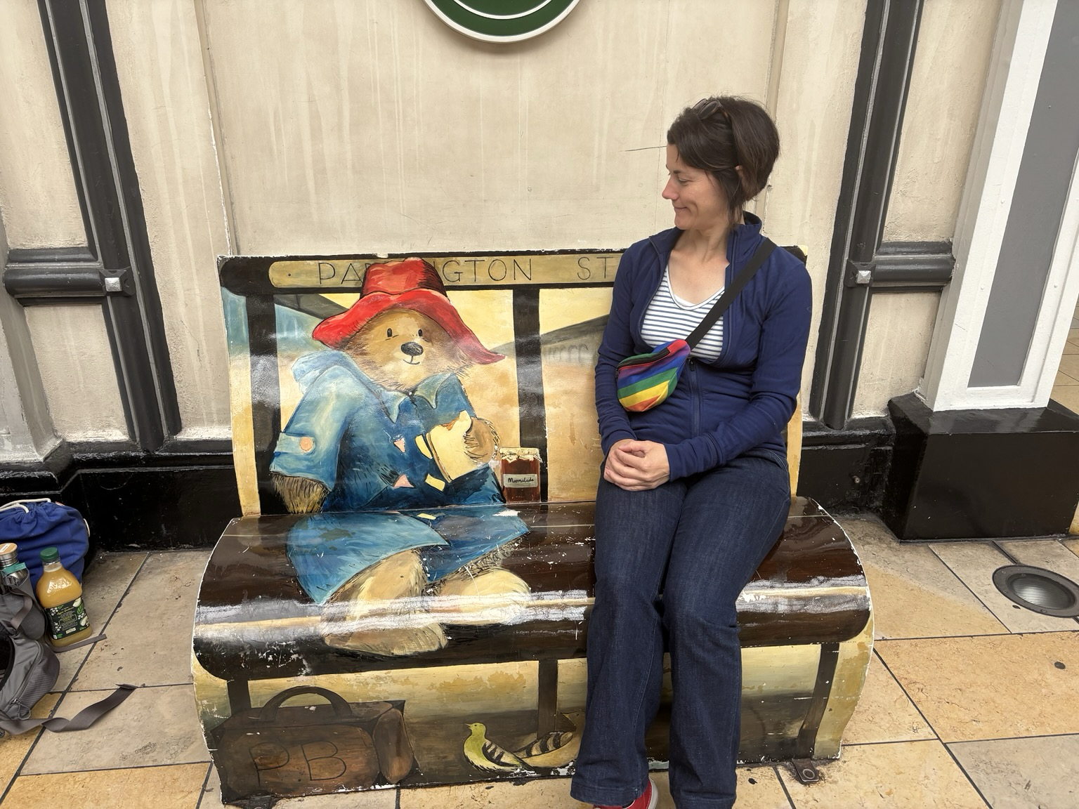 Judith auf einer Bank auf die „Paddington“ der Bär gezeichnet ist