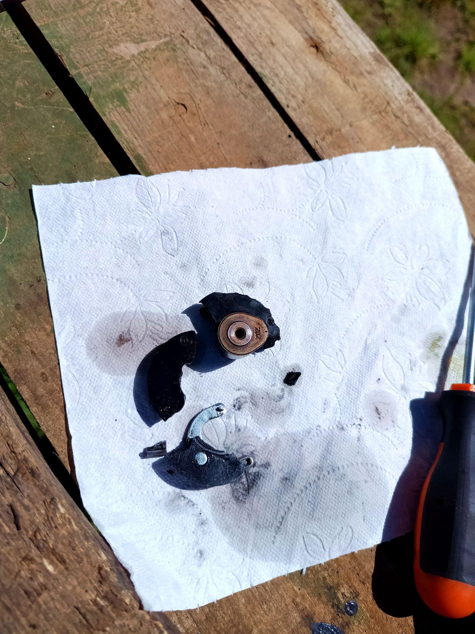 The old timing pulley, in pieces. There's three large plastic shards, a few small splinters, the cam and some other metal parts for a centrifugal decompression feature that made nothing but trouble.
