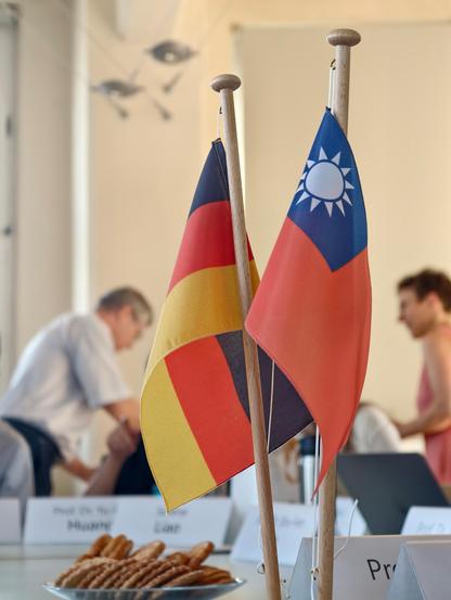 Snapshot of the German and Taiwan flags that reside in the middle of a table, snacks nearby 