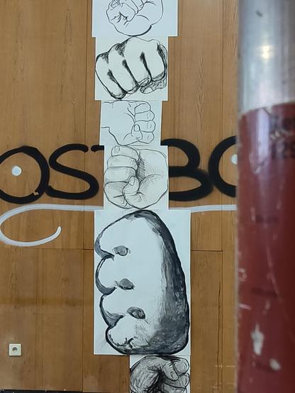 Unterschiedliche Zeichnungen von Fäusten vor einer Holzwand, Teil der Ausstellung über die Kunstausstellungen der DDR