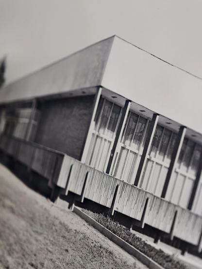 Eine S/W-Fotographie der Robotron-Kantine aus dem Jahr 1979, schief fotografiert. Ein rechteckiges einstöckiges Gebäude auf Podest