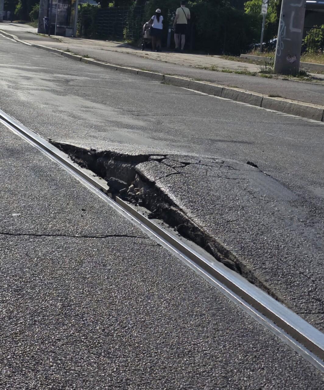 Aufgequollener Asphalt direkt an einer Straßenbahnschiene. Zwei Schollen Asphalt sind über zehn Zentimeter nach oben aufgebrochen. Eine Bahn kann dort nicht mehr fahren.