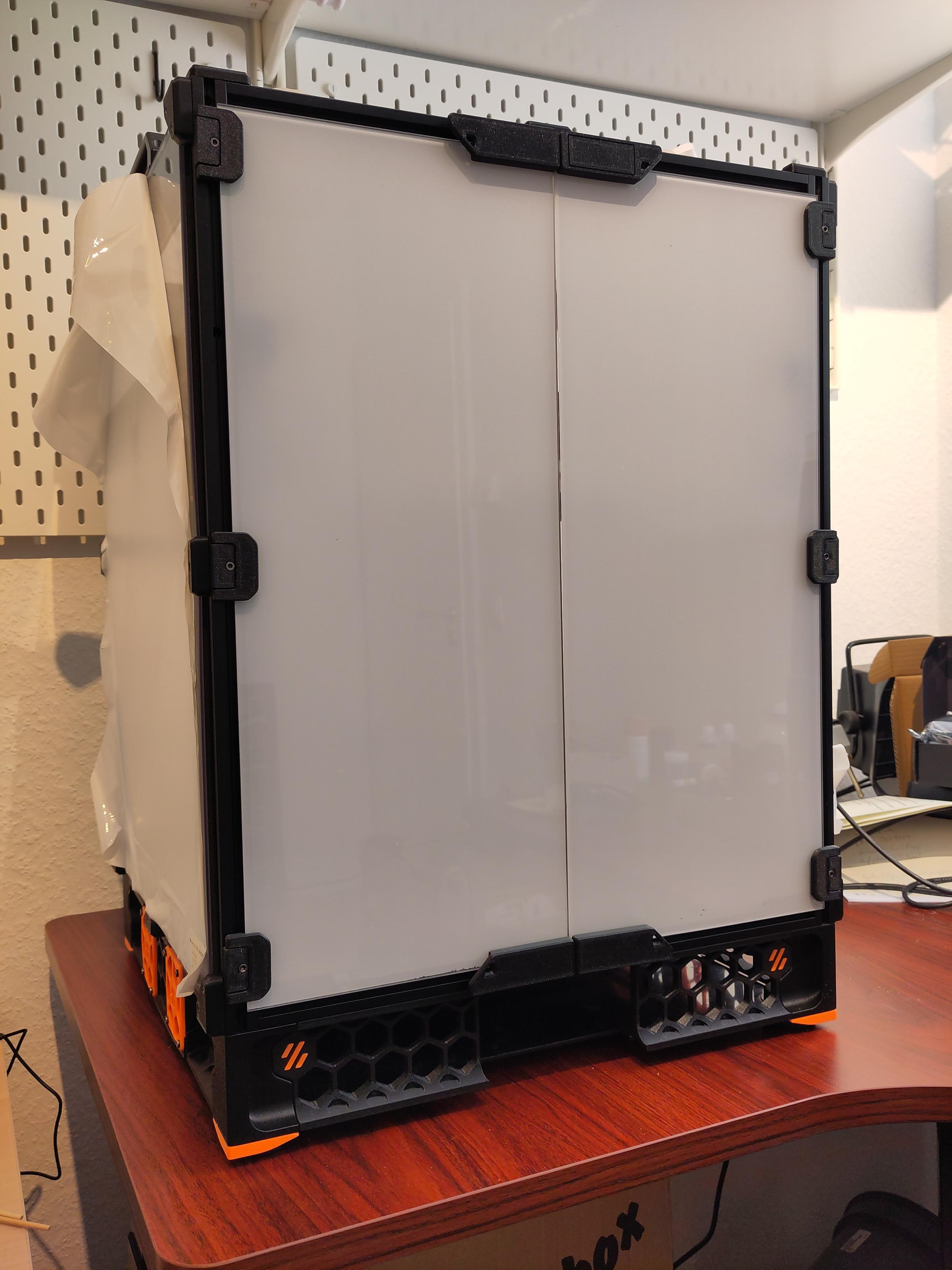 A Voron Trident 3D printer with installed panels and doors. The protective films are still on the acrylic panels, so that the inside of the printer cannot be seen.