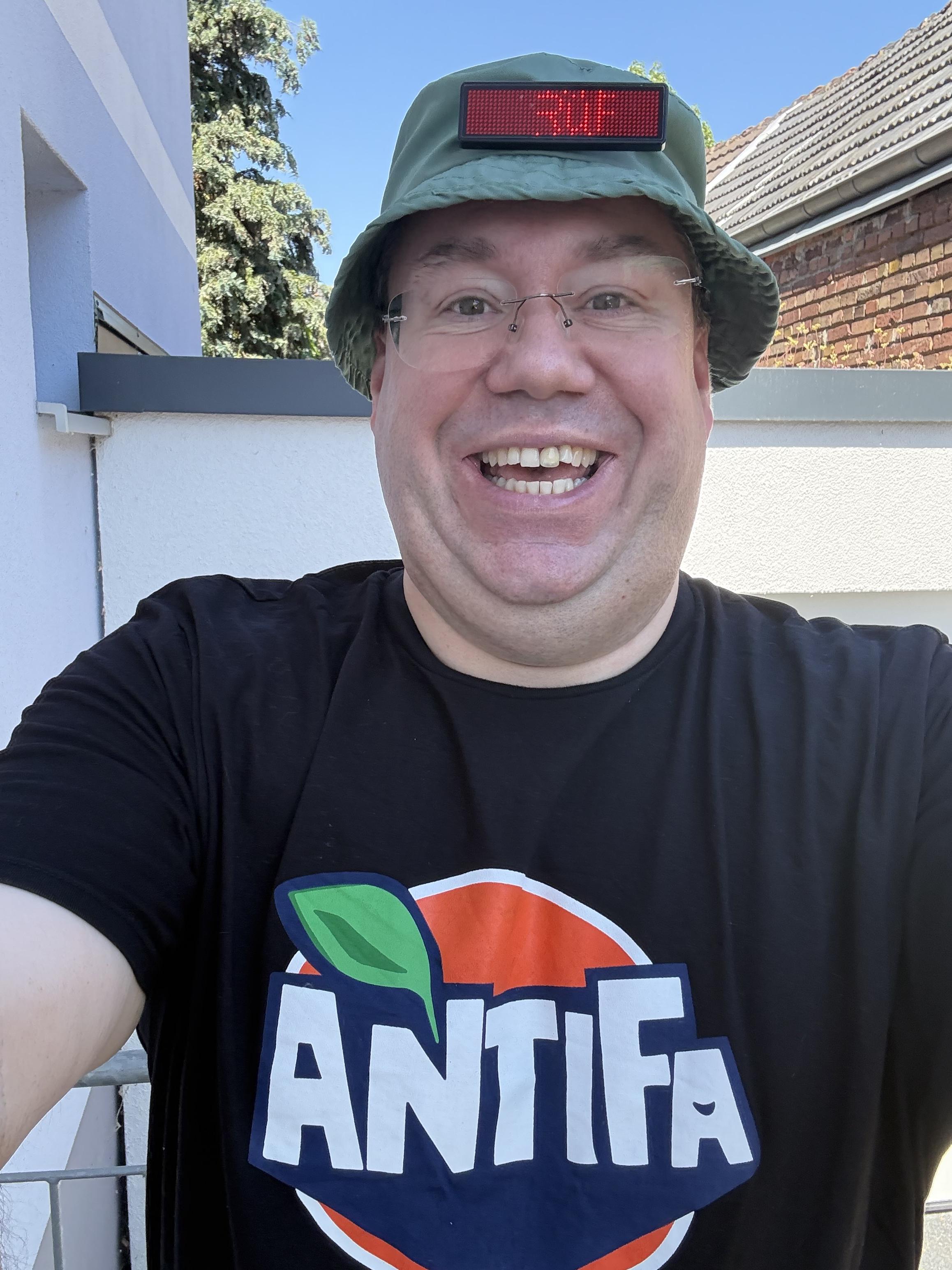 Foto von mir mit Sonnenhut mit LED-Prüf-Laufschrift und dem ANTIFA-Logo in Limo-Logo-Erscheinung