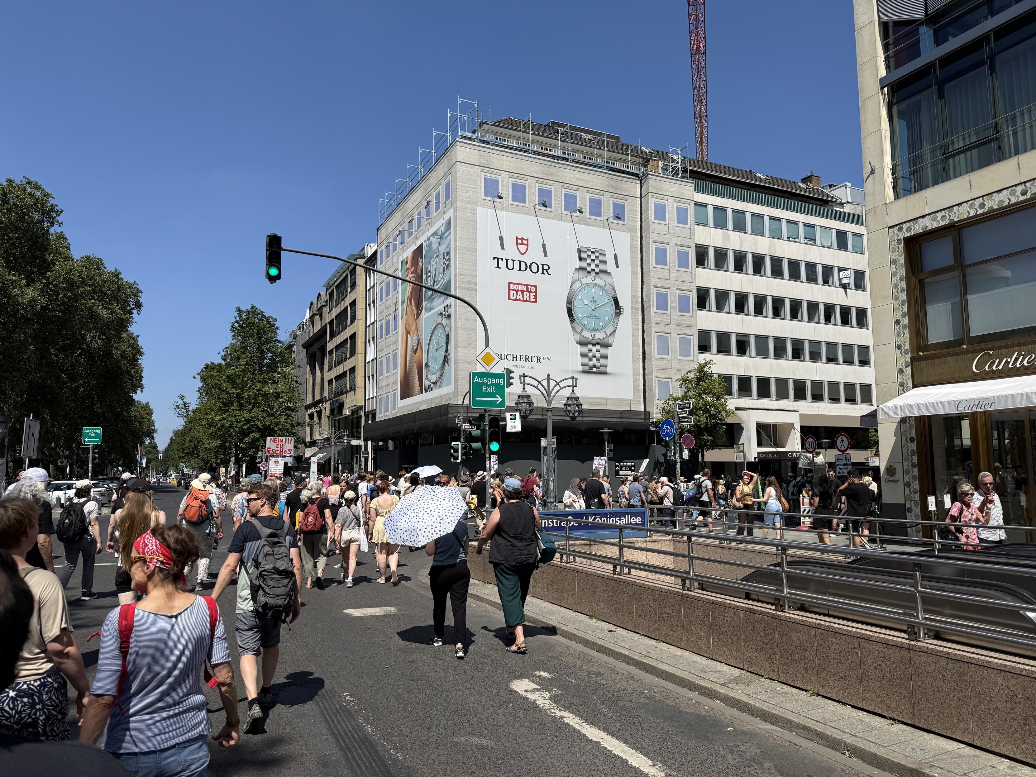 Beim Abbiegen auf die Steinstraße beschwerte sich unser »DJ der guten Laune« darüber, dass rechts abbiegen nicht so gut zu einer Prüfdemo passt.

Zu sehen ist unser Demozug der die Straße füllt. Menschen schützen sich u. a. mit Regenschirmen gegen die Sonne. Auch hier haben wir einen wolkenlosen blauen Himmel – den wir trotz der Hitze viel lieber als die blaue Partei haben … 😝