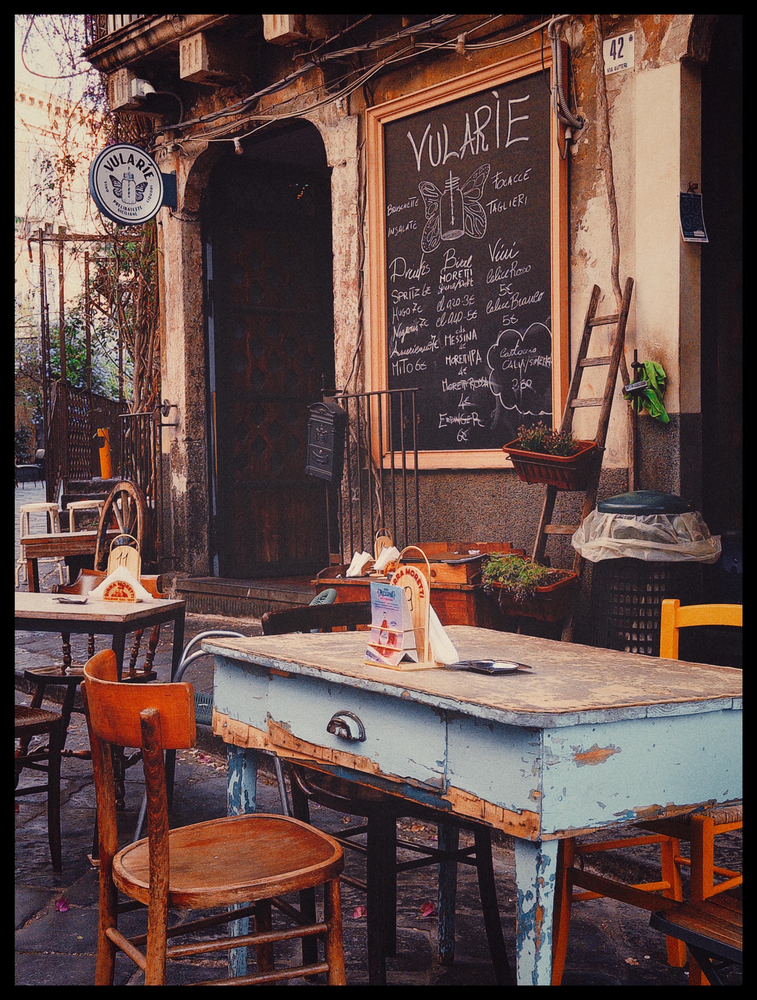 Gemütliches Straßencafé mit alten Tischen und Stühlen und gerümpligem Eingang
