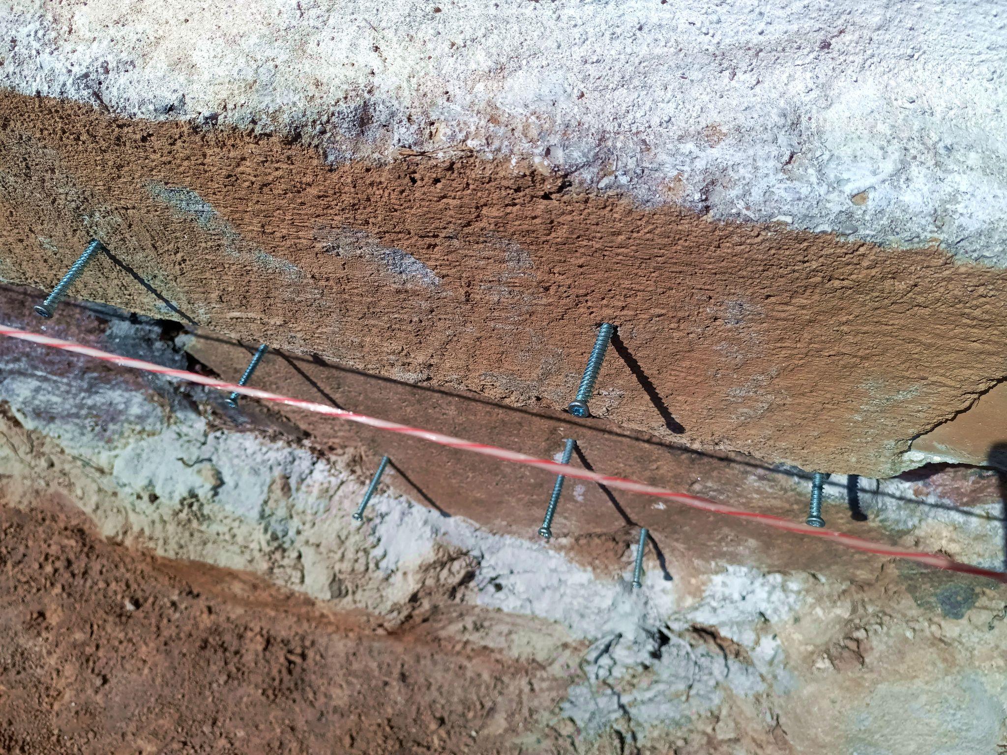 Bit anchor bolts are installed in the old foundation. Directly into the rocks at the bottom and through the old concrete and into the rock beneath at the top. A guide string is stretched across.