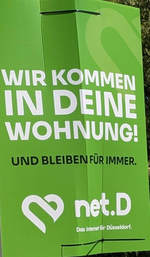 Grünes Werbeplakat von net.D auf dem steht:
Wir kommen in deine Wohnung!
Und bleiben für immer.
