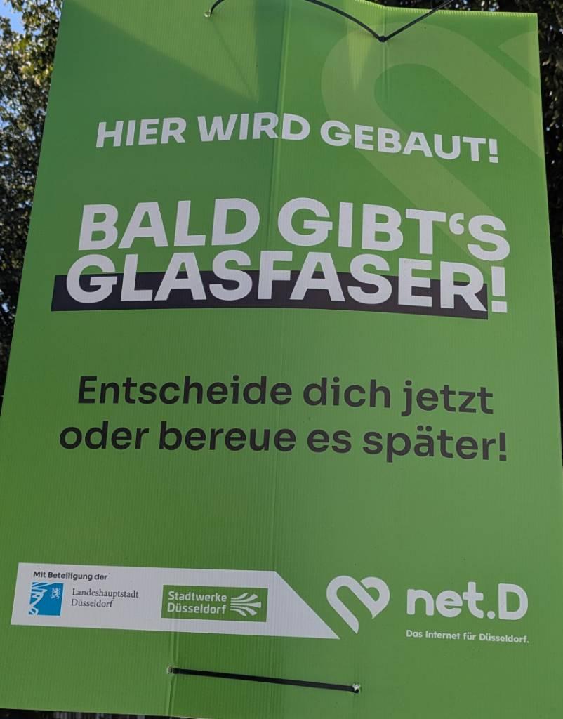 Grünes Werbeplakat von net.D auf dem steht:
Hier wird gebaut!
Bald gibt's Glasfaser!
Entscheide dich jetzt oder bereue es später!