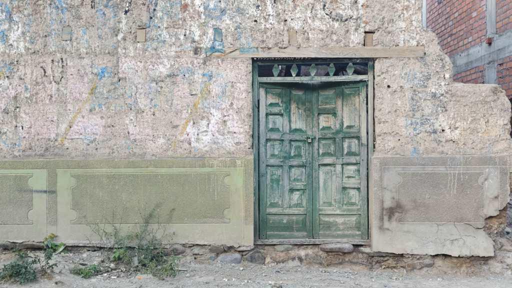 Verschlissene grüne Tür in einer Wand.