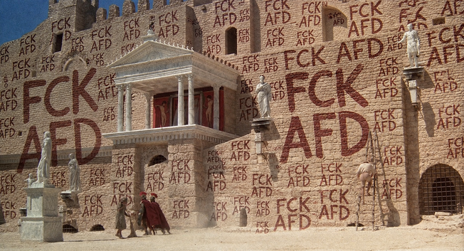 Screenshot aus "Das Leben des Brian".
Statt "romanes ite domum" steht "FCK AFD" an der Mauer.
(Mit Sicherheit KI-genriert.)