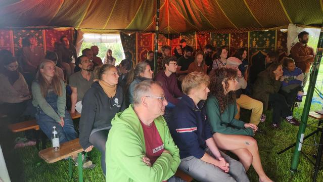 Foto von Zuschauenden in einem bunten Zelt auf einer Wiese